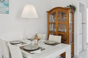 a white dining room with a table and a china cabinet at Nuestra Casa in Denia