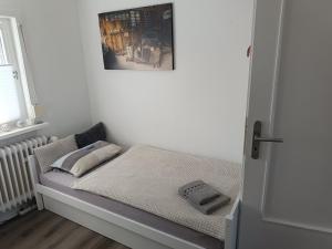 a small bed in a white room with a window at Ferienwohnung Harz Valley -Mit Fernblick in den Harz. in Goslar