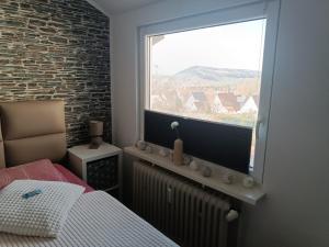 a bedroom with a bed and a large window at Ferienwohnung Harz Valley -Mit Fernblick in den Harz. in Goslar