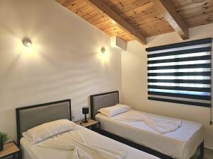zwei Einzelbetten in einem Zimmer mit Fenster in der Unterkunft Villa Arta Apartments in Sarandë