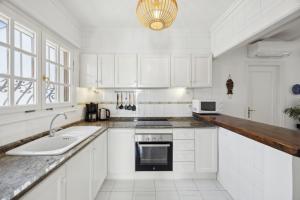 a white kitchen with a sink and a microwave at Nuestra Casa in Denia +16 photos