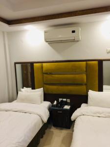 Una habitación de hotel con dos camas con sábanas blancas. en Shanze Hotel And Suites, en Lahore