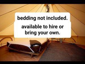 a bed in a tent with a sign that readsidding not includedatable to hire at The Paddock Wildcamp in Perranporth
