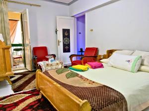 a bedroom with a bed and two red chairs at Gadou Rooms -Private & Shared Stays in Port Said Best Location in Port Said