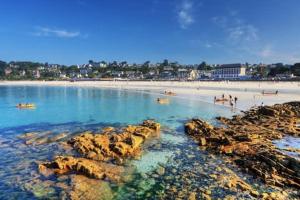a beach with rocks and people in the water at Magnifique appartement plage de Trestraou in Perros-Guirec