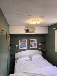 a bedroom with a white bed and a green wall at Mobilhome Metanova in Camiers