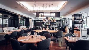 a restaurant with wooden tables and chairs and a kitchen at Holiday Inn Mulhouse by IHG in Mulhouse