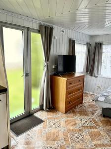 a bedroom with a tv on a wooden dresser with a window at Domek Holenderski in Mielno