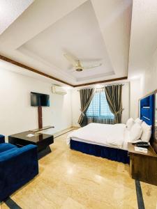 a hotel room with a bed and a blue couch at Shanze Hotel And Suites in Lahore