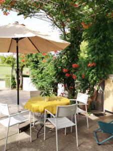 a yellow table with chairs and an umbrella at Gîte en Provence ''Rose'' in Modène
