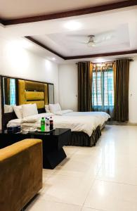 a hotel room with two beds and a couch at Shanze Hotel And Suites in Lahore +17 photos