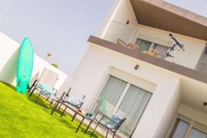 a house with a surfboard sitting on the lawn at Wayra Lodge [Kanchay] in Raposeira