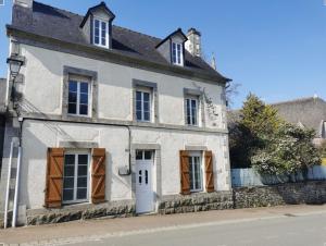 an old white house with brown doors and windows at L'Astu'Cieux appartement triplex in Huelgoat