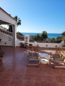 eine Terrasse mit zwei Stühlen und einem Tisch und dem Meer in der Unterkunft Torrox Beach Club in Torrox