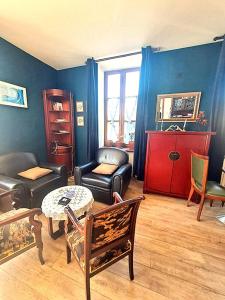 a living room with leather furniture and a table at Les Chambres de la Violette in Grenier-Montgon