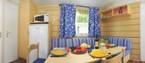 a kitchen with a table and a table and a refrigerator at Camping 4 étoiles - Parc aquatique - eeia0i in Le Bois-Plage-en-Ré