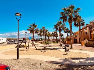 a park with a playground with palm trees and swings at La Casa del Violín in Pilar de Jaravía