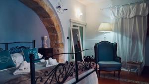a bedroom with a bed and a chair and a window at Antica Dimora San Girolamo in Licata