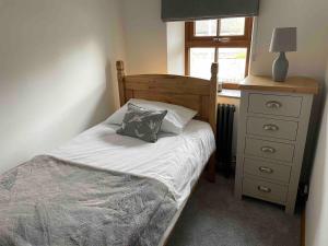 a bedroom with a bed with a pillow and a dresser at Renovated 2 bed Cottage in Ulverston, Garden with Views in Ulverston