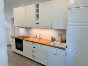 eine weiße Küche mit weißen Schränken und einer Spüle in der Unterkunft City & Sea - Apartamenty i Mieszkania in Gdynia + 39 Fotos