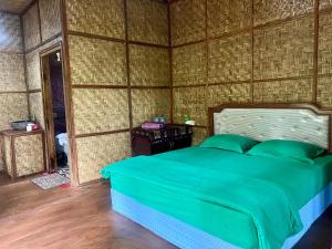 a bedroom with a green bed in a room at Joben Ecolodge in Tetebatu