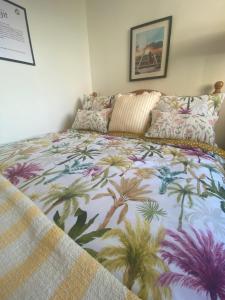 a bedroom with a bed with a colorful bedspread with palm trees at R and B Cosy Cabin in Clooney Park