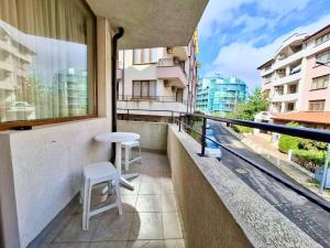 a balcony with a table and two white stools at Stamopolu Apartments in Primorsko