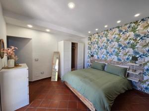 una camera da letto con un letto verde e una parete floreale di Your nest on the Path a Positano