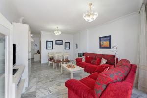 a living room with a red couch and a table at Al Mar Los Gigantes in Puerto de Santiago