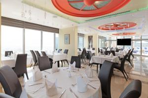 a restaurant with white tables and chairs and a tv at Oryx Hotel in Abu Dhabi
