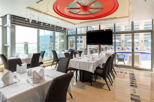 a restaurant with white tables and chairs and a large clock at Oryx Hotel in Abu Dhabi