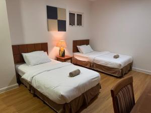 a room with two beds and a lamp in it at Gateways Apartment 6pax, Kuching Waterfront in Kuching