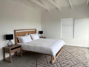 a white bedroom with a large bed and a table at 101 Fairways in Stompneusbaai +44 photos