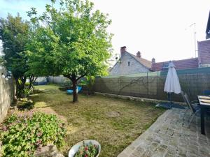 Un patio trasero con un árbol y una sombrilla. en L'Ecrin de Pierres en Campagne, en Baron 10 fotos más