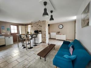Una sala de estar con un sofá azul y una cocina. en L'Ecrin de Pierres en Campagne, en Baron