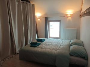 Un dormitorio con una cama con dos almohadas azules encima. en L'Ecrin de Pierres en Campagne, en Baron