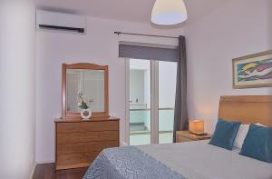 a bedroom with a bed and a mirror and a dresser at Downtown Praia da Vitória AL in Praia da Vitória