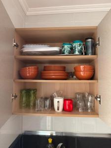 a kitchen shelf with plates and bowls and dishes at Appartement Nador in Nador