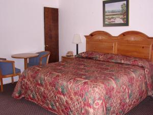 a hotel room with a bed and a table and chairs at Red Carpet Inn & Suites Morgantown in Morgantown