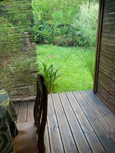 a wooden deck with a chair in a yard at les petits galets in Sainte-Rose +5 photos