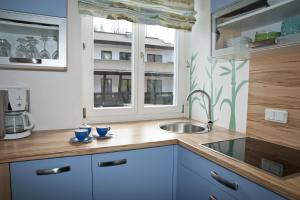 a kitchen with blue cabinets and a sink and a window at Haus Zinnauer in Velden am Wörthersee