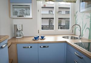 a kitchen with blue cabinets and a sink and a window at Haus Zinnauer in Velden am Wörthersee