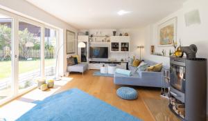 a living room with a couch and a tv at Sonniges modernes ruhiges grosses Haus Garten Pool in Oberhaching