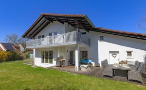 a white house with a deck and a patio at Sonniges modernes ruhiges grosses Haus Garten Pool in Oberhaching