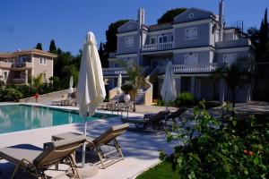 a pool with chairs and umbrellas in front of a building at The Seven Islands Deluxe Apartments in Gouvia