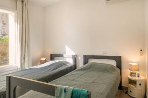 two beds in a bedroom with a window at Magnifique villa familiale avec piscine in Brando +8 photos