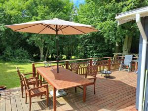 a wooden table with an umbrella on a deck at Cottage With Spa Near Sommerland Sjælland in Højby