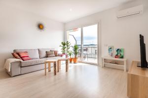 a white living room with a couch and a table at Apartamento artístico Vilanova in Vilanova i la Geltrú