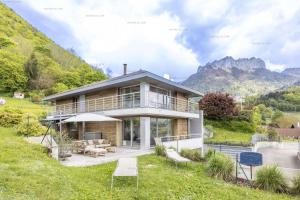 una casa en una colina con montañas al fondo en Menthon saint Bernard Heights, en Menthon-Saint-Bernard