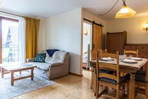 a living room with a table and a couch at TatryTop Apartamenty Pardałówka in Zakopane